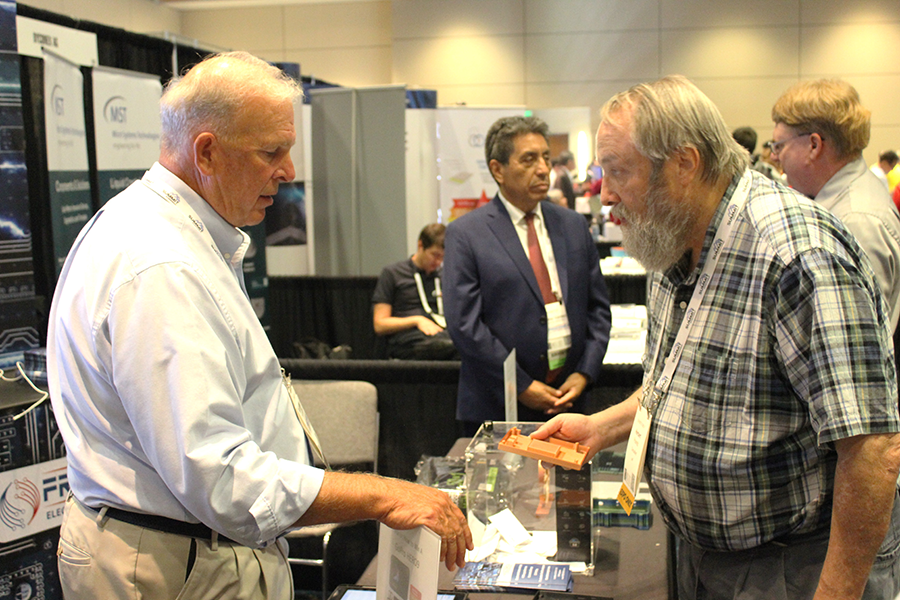 Freedom CAD COO Scott Miller speaks to a exhibition visitor at PCB West 2023. 